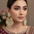 Pair of gold and pearl earrings on a black background