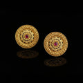 Pair of gold earrings with red gemstones on a dark surface