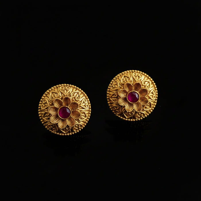 Pair of gold earrings with pink gemstones on a gray background