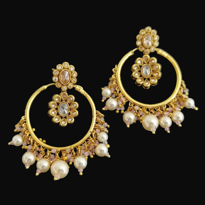 Gold and pearl earrings on a dark background