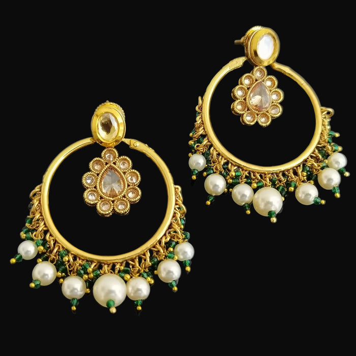 Gold earrings with pearls and green stones on a black background