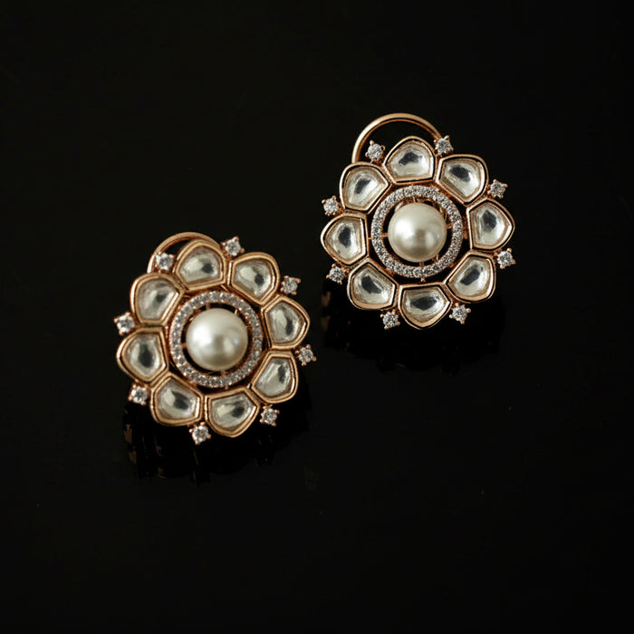 Pair of gold and pearl earrings on a black background