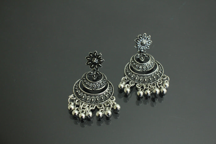 Pair of silver earrings with intricate designs on a dark background