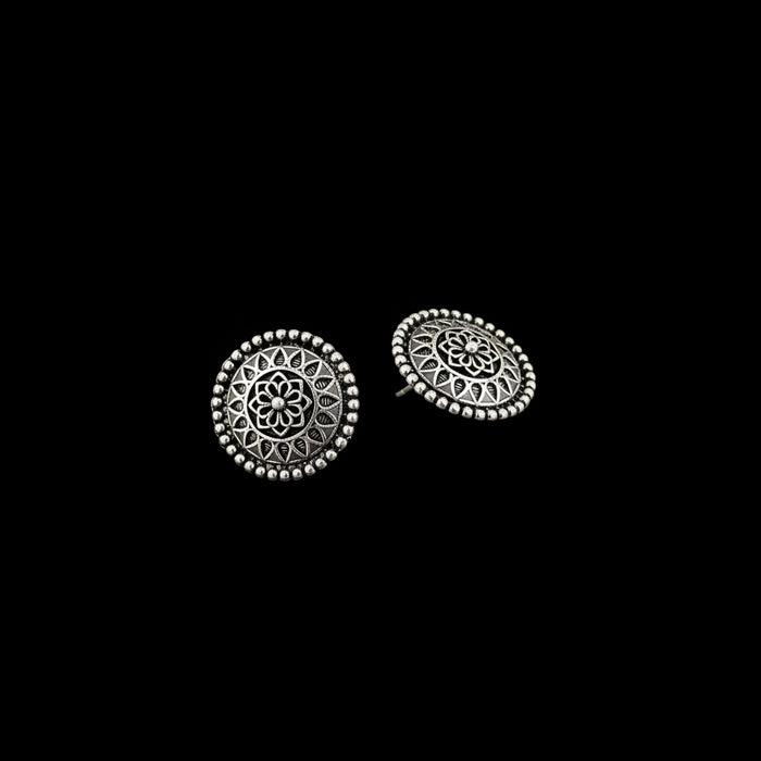 Pair of silver stud earrings with intricate designs on a gray background