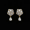 A pair of gold-toned statement earrings with clear gemstones, displayed on a black stand against a gray background with the brand name 'SAHELI MY BEST FRIEND' at the top.