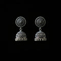 Silver jhumka earrings on a peacock feather with a dark background