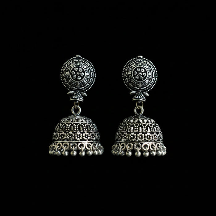 Ornate silver earrings on a peacock feather