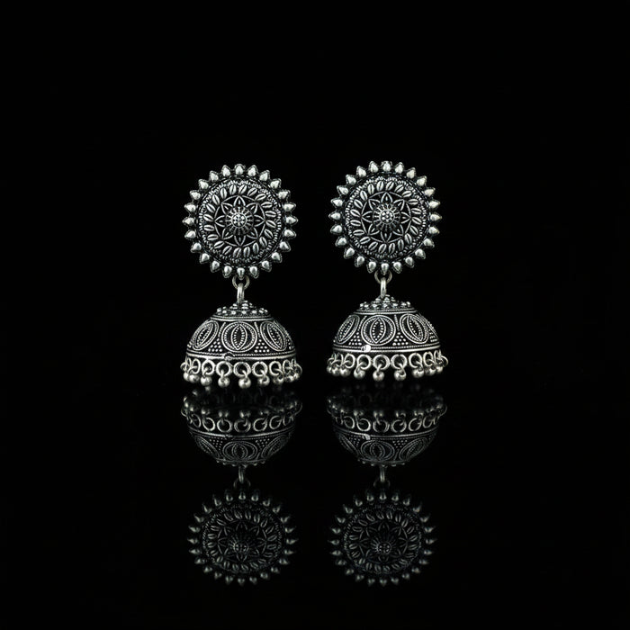 Silver earrings on a peacock feather with a dark background
