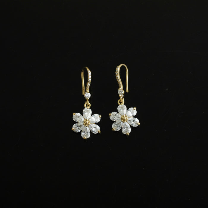 Pair of gold flower-shaped earrings on a black background