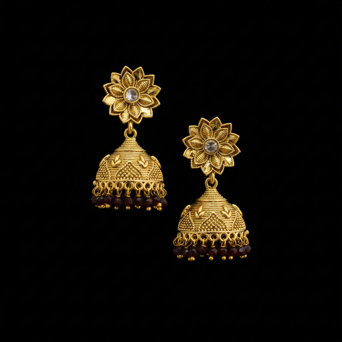 Gold floral earrings on a black stand with a gray background