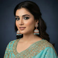 Gold and turquoise earrings on a black stand with a black background