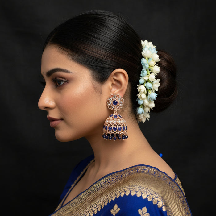 Pair of ornate earrings with blue and clear gemstones on a dark background