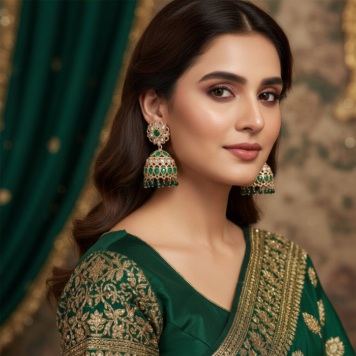 Pair of green and gold earrings on a dark background
