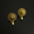 Pair of gold earrings with pearl accents on a black background