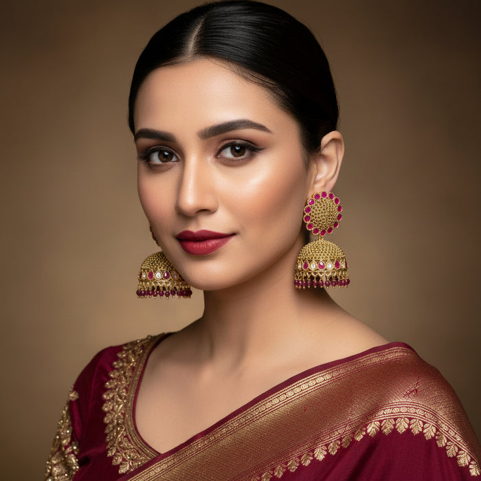 Gold and pink earrings on a gray stand with a black background