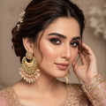 Pair of gold and pearl earrings with pink stones on a black background