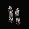A pair of ornate Indian chandbali earrings featuring large red gemstones and clear stones in a silver-tone setting, displayed on a dark reflective surface. The brand logo 'SAHELI MY BESTFRIEND' is visible in the top left corner.