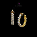 Gold hoop earrings with embedded stones on a gray background, branded 'Saheli'.