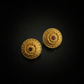 Pair of gold earrings with red gemstones on a black background