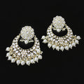 Pair of ornate earrings with pearls on a dark background