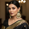 Pair of ornate earrings with pearls and black stones on a dark background