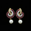 Pair of gold and red gemstone earrings with pearls on a dark background, branded 'Saheli'.