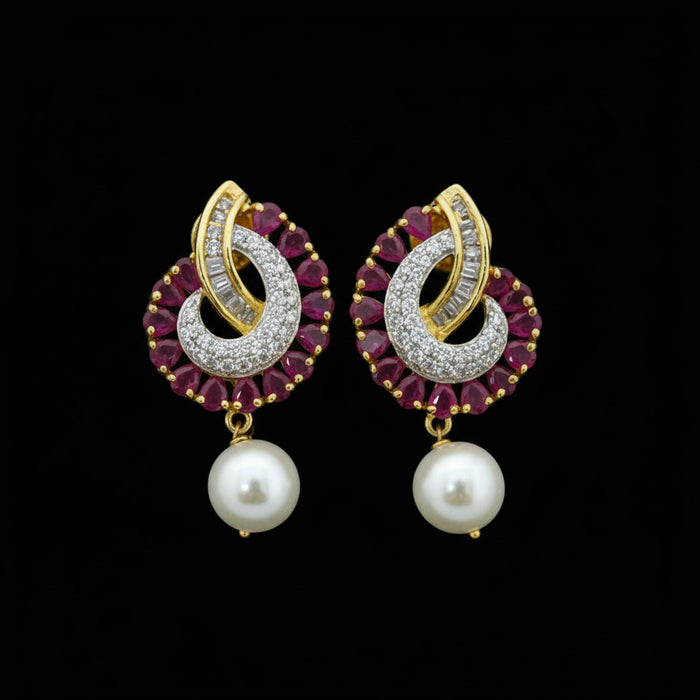 Pair of gold and red gemstone earrings with pearls on a dark background, branded 'Saheli'.