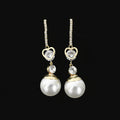 Pearl and diamond earrings on a black stand against a dark background