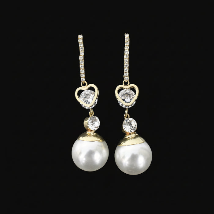 Pearl and diamond earrings on a black stand against a dark background