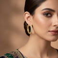 Gold hoop earrings with clear stones on a black background