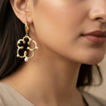 Gold earrings with pearl-like beads on a dark background