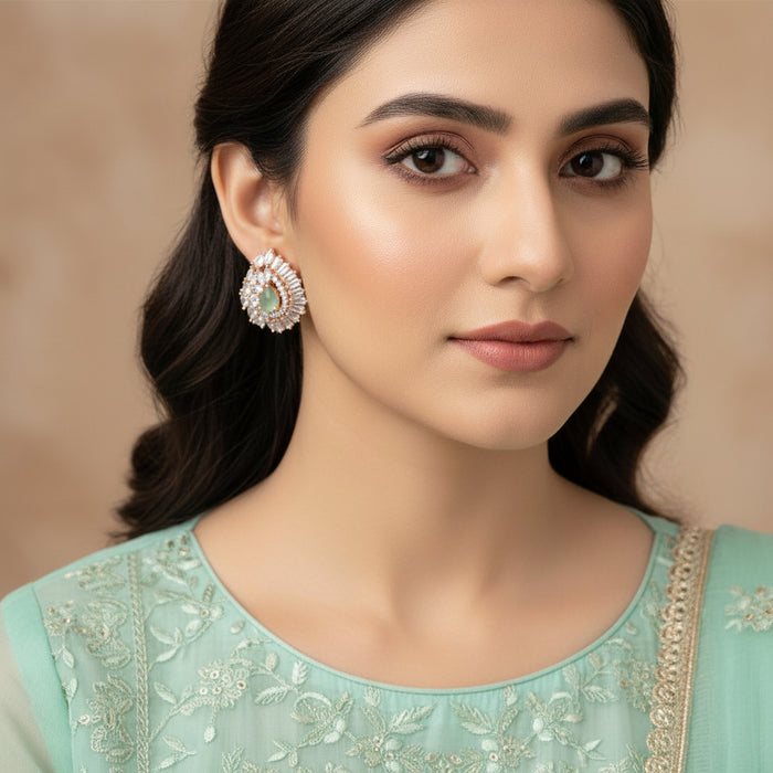 Teardrop-shaped earrings with gemstones on a dark background, featuring the brand 'Saheli'.