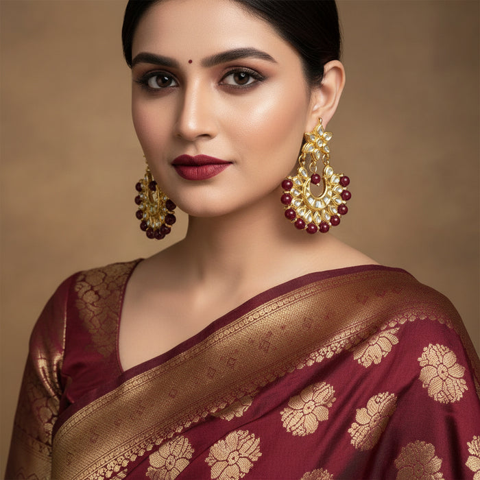 Gold and red earrings on a dark background with 'Saheli' branding.