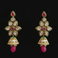 A pair of gold-plated Indian jhumka earrings with pink stone accents, clear crystals, and green enamel details, displayed on a black Y-shaped stand against a gray background. The brand logo 'SAHELI MY BEST FRIEND' is visible at the top.