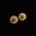 Gold floral earrings with red gemstones on a gray background, featuring the 'Saheli' brand.