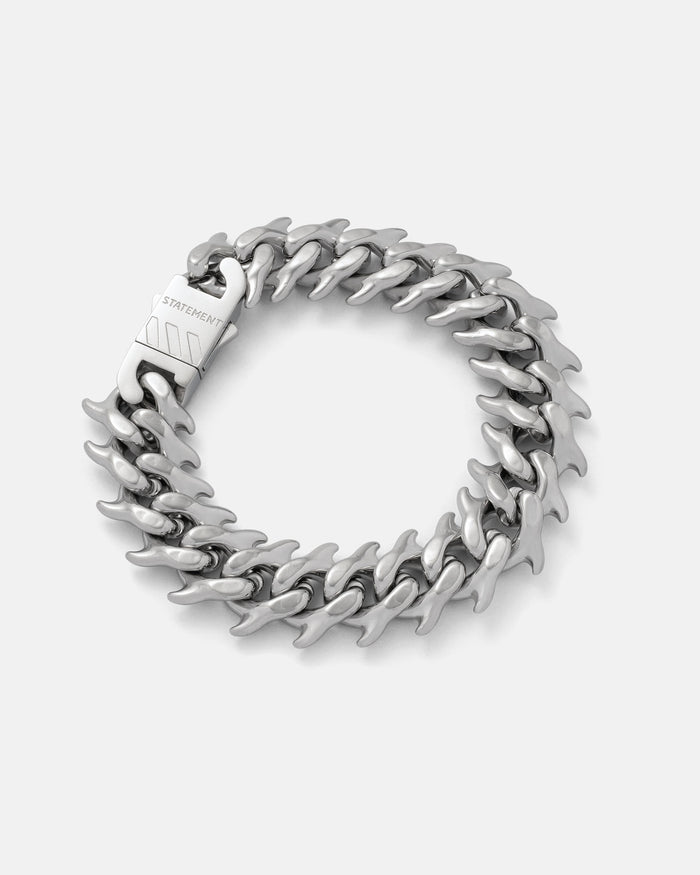 Silver 11mm Spiked Cuban Bracelet with curved spikes by statement collective on grey background.