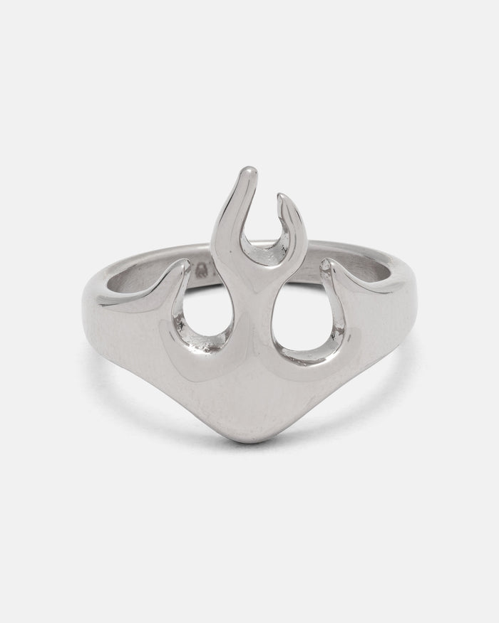 The Statement Collective Flame Ring is a silver stainless steel accessory showcasing a striking flame-shaped design at its center, set against a plain white background. This bold streetwear ring is also hypoallergenic, ensuring comfortable wear every day.