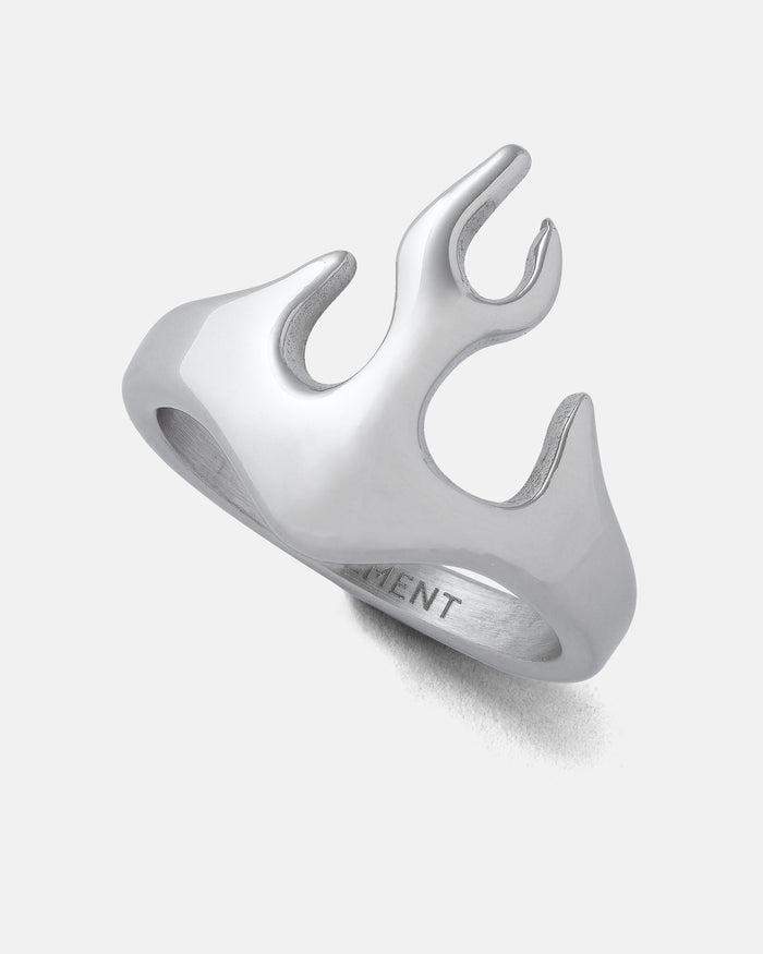 The Statement Collective Flame Ring is a silver stainless steel accessory that showcases an abstract, flame-inspired design with smooth, flowing curves, making it the perfect bold addition to any streetwear look. Photographed against a plain white background.