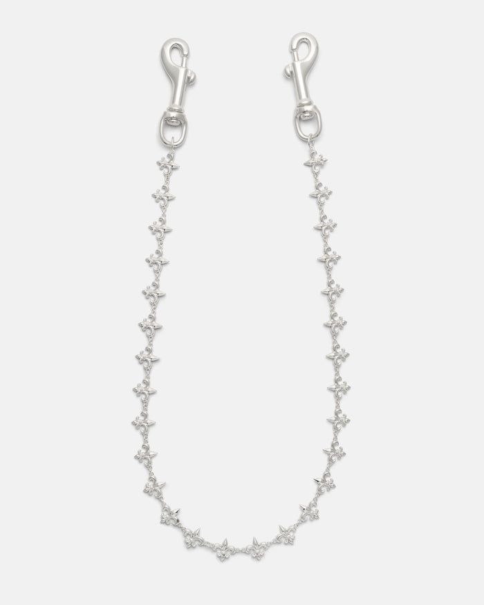 Introducing the “Fleur De Lis” Wallet Chain by Statement Collective—a delicate silver accessory featuring small, evenly spaced star-shaped links and metal clasps at each end. Displayed against a white background, its intricate design evokes refined elegance and offers a subtle nod to the classic motifs found in traditional Fleur De Lis wallet chains.