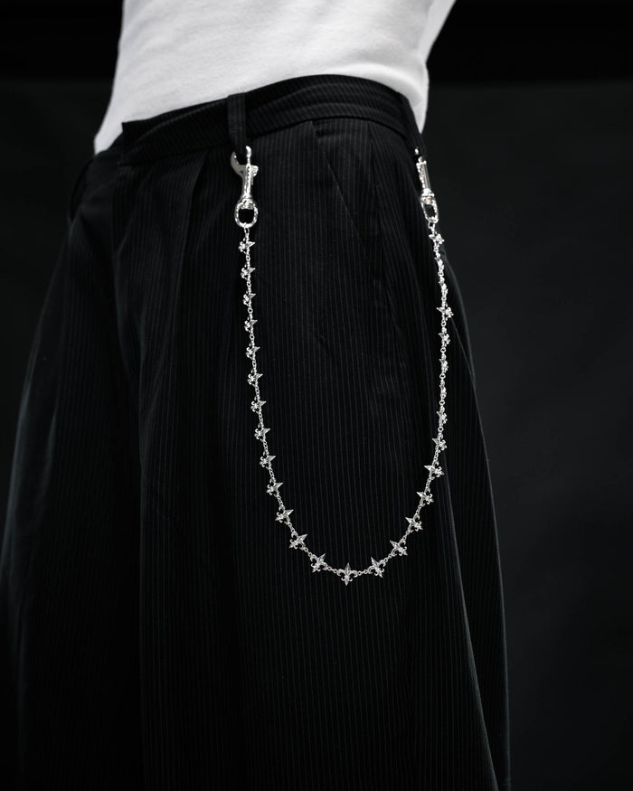 A person wearing black pinstripe pants with the Statement Collective “Fleur De Lis” Wallet Chain attached to the belt loops, photographed against a dark background.