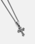 The Statement Collective French Cross Pendant, featuring dotted patterns, hangs from a sleek figaro chain and is displayed on a plain light grey background.