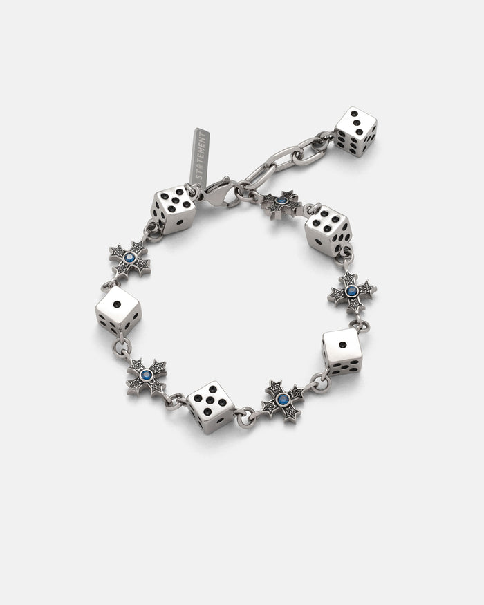 The Gambler’s Faith Bracelet by Statement Collective showcases silver six-sided dice and star-shaped links with blue centers, arranged in an alternating pattern, displayed on a plain light background.