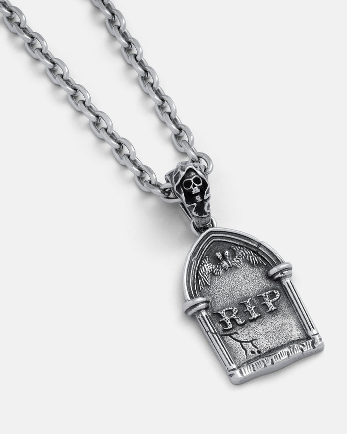The Gravestone Pendant is a silver chain necklace with a tombstone-shaped pendant featuring "RIP," angel wings, and a small skull—perfect for fans of grim jewelry.