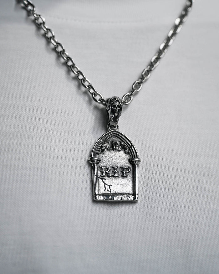 The Gravestone Pendant in silver, engraved with RIP and topped with a tiny skull, adds a touch of grim style when worn over a plain white shirt.