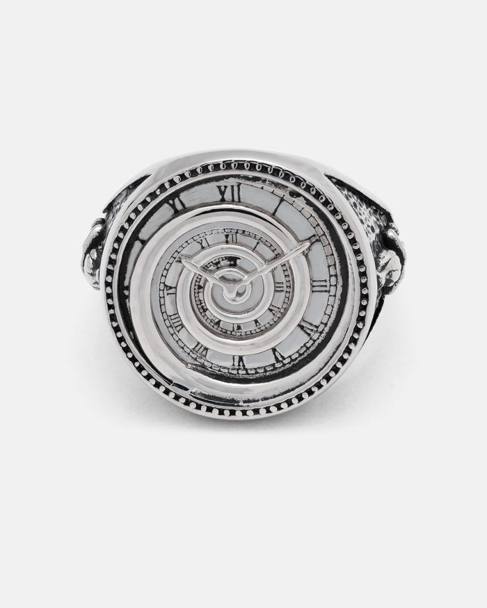 The Infinite Clock Ring by Statement Collective is a silver ring crafted with a detailed spiral clock face, Roman numerals, clock hands, and a mesmerizing spiral pattern at its center.