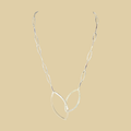 Leaf pendant necklace in sterling silver by Grace Chin, shown on a desert plaster background