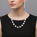 Pearl necklace and earrings set on a black stand with 'SAHELI' branding.