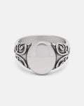 The Mini Oval Scroll Signet Ring by Statement Collective features a polished silver centerpiece and an ornate traditional scroll pattern swirling along the band, displayed on a plain white background.