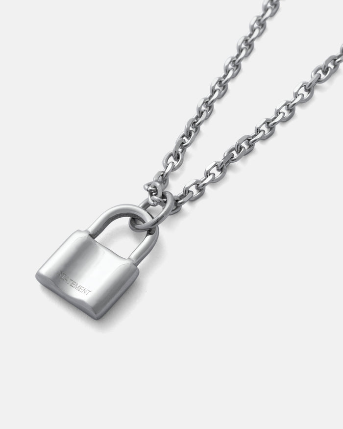 The Mini Padlock Pendant is a silver necklace with a shiny padlock charm, displayed on a plain light gray background and suspended from a delicate 2mm chain.