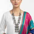 Silver necklace with intricate designs on a reflective surface